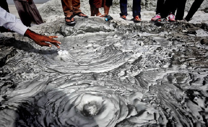 a man touching spring of mud volcano, Chabahar attraction, Iran 
